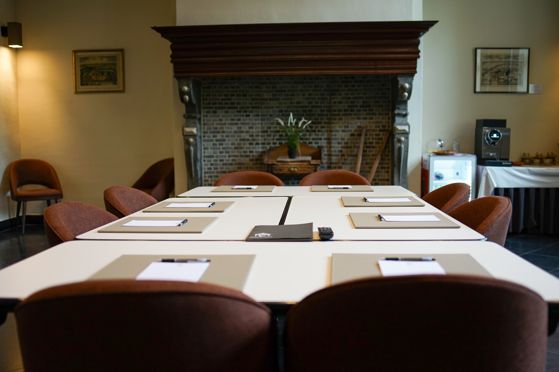 Vergadertafel opgesteld bij een historische schouw in een meetingzaal van Priorij Corsendonk